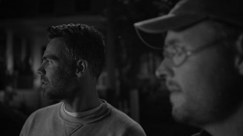Josh Janssen and Tommy Jackett lit in red and blue light, shown here in black and white